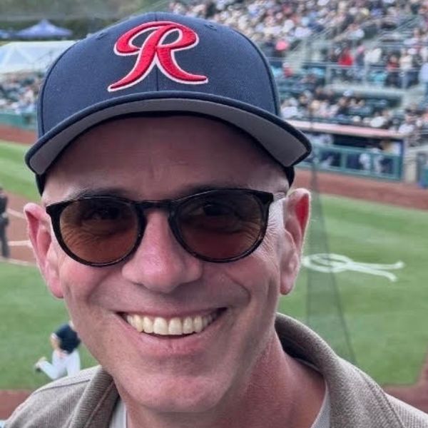 headshot of Nick Wingfield wearing a Tacoma Rainiers baseball cap and sunglasses.